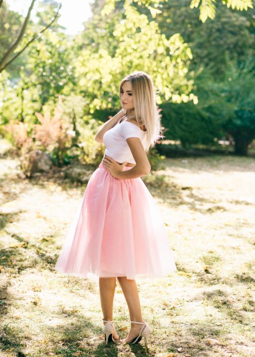beautiful girl in pink skirt standing in the park